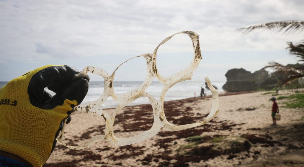brian-yurasits-Nk85jPGgVsM-unsplash plastic free featured image - man holding plastic 6 ring on beach