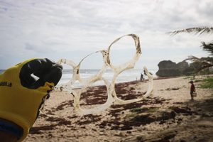 plastic free featured image - man holding plastic 6 ring on beach