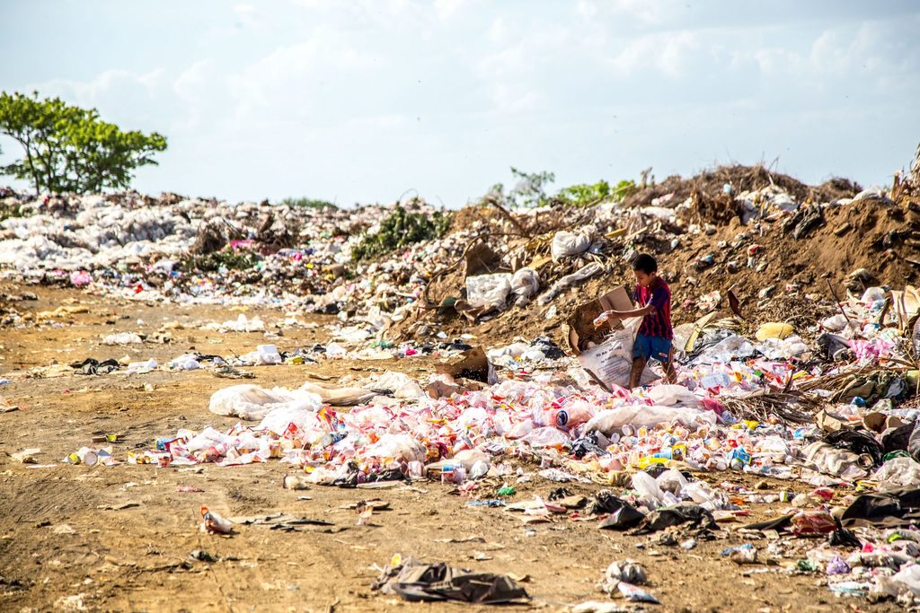 plastic-free body image 1 - beach covered in plastic with small boy walking through