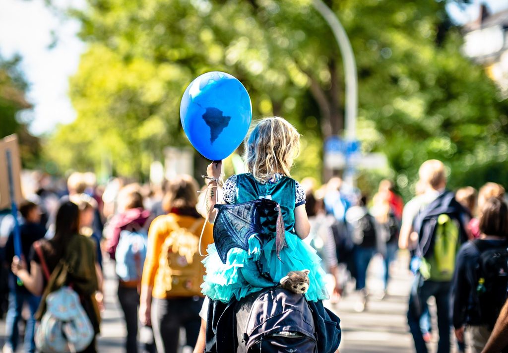 positive climate action girl on the shoulders of a parent with a balloon of the globe